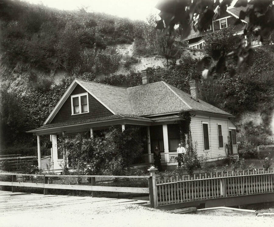Exterior view of a home in Wallace, Idaho. A woman and man can be seen standing on the front porch.