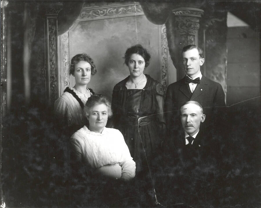 Portrait of the McComb Family. Back row (from left to right): Mrs. Max Richardson Crosby (n��e Effa McComb, daughter), Mrs. Claude Babin (n��e Mildred McComb, daughter), John Floyd McComb (son). Front row (from left to right): Sarah Downs McComb (mother), Dougal McComb (father). Mildred's children James and Eugene Babin both graduated from University of Idaho. A crack in the glass negative can be seen in the resulting print.
