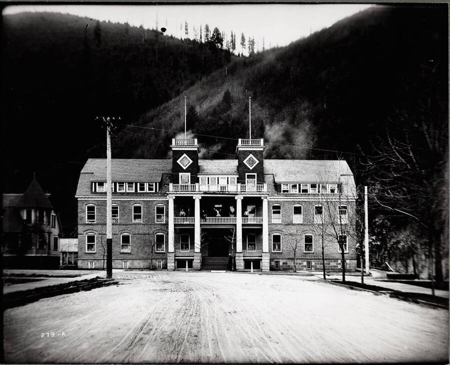 Exterior view of the hospital in Wallace, Idaho. Several people are standing on the 2nd floor balcony.