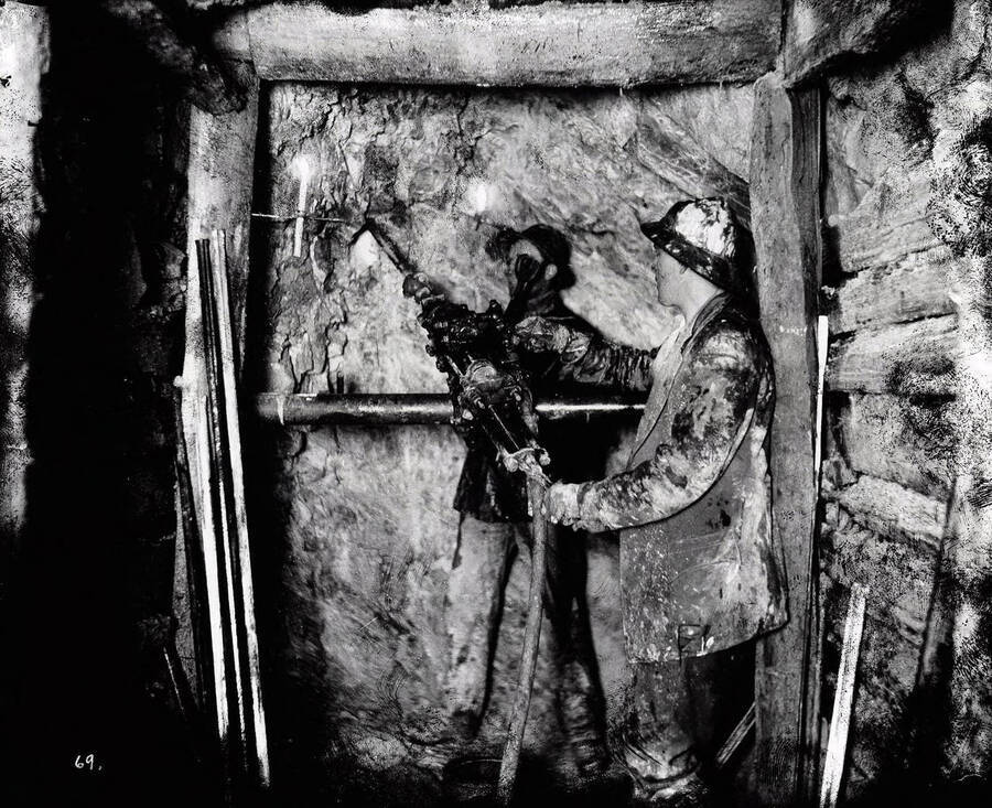 Image is of miners drilling for ore samples underground using hand crank liner.