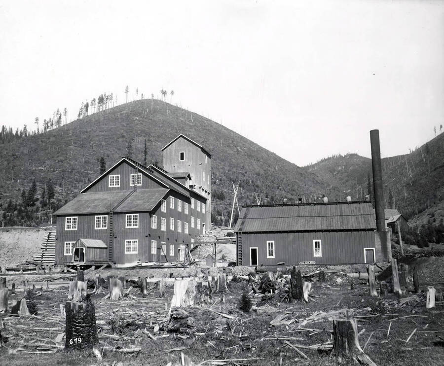 Exterior view shows the Hunter Mill near Mullan, Idaho and clear cut hills and tree stumps.
