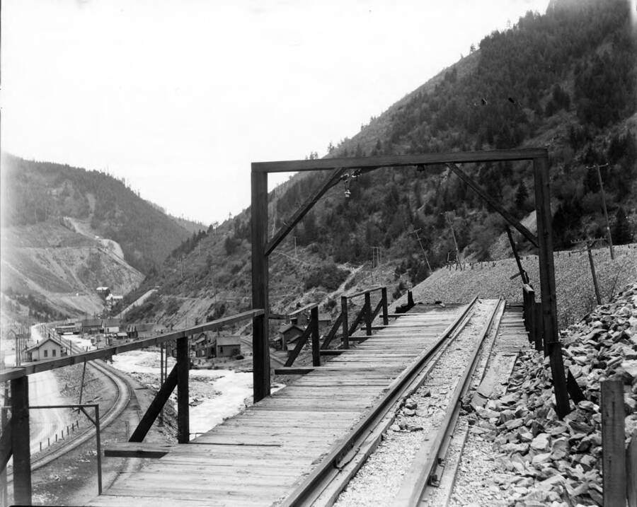 Image shows railroad tracks and surrounding scenery of houses and river.
