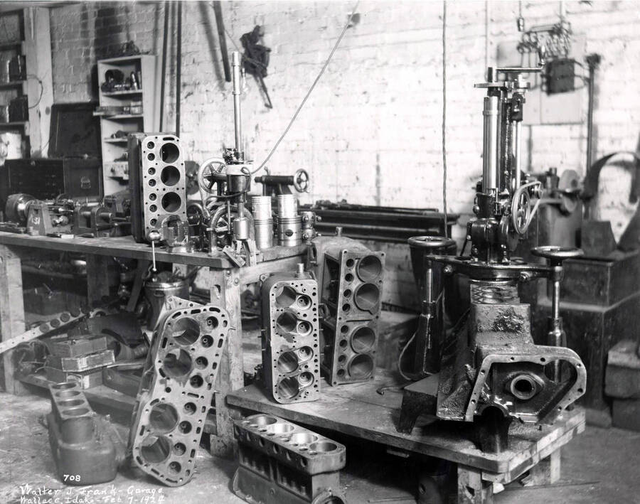 Interior view of the work area for the Walter J. Frank Garage. Image shows automobile engines and machinery. February 14, 1924.