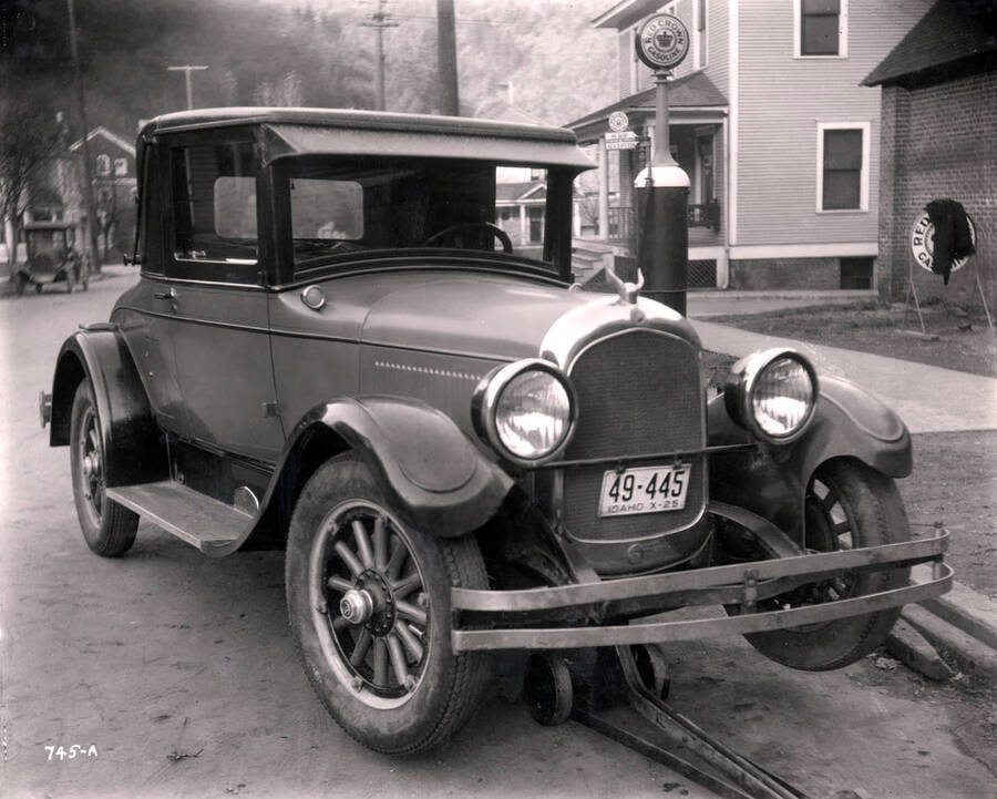 Image shows Art Whaley's car raised on a jack, Wallace, Idaho, March 1925.