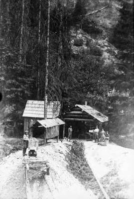 Showing group of men in front of mine entrance.