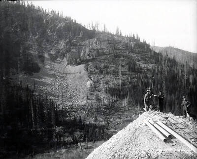 Men are seen standing around an ore car.