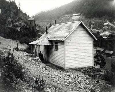 George Nick sitting on porch of house in Burke, Idaho.