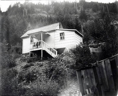 George Nick sitting on porch with dog of house in Burke, Idaho.