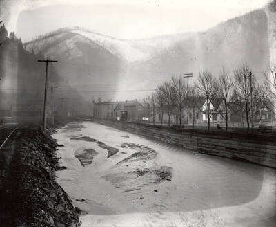 The Coeur d'Alene River with buildings and the railroad along the bank near Wallace, Idaho. Taken for H.L. Day.