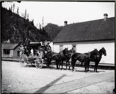 Caption on back: "Mullan Stage, but photo taken in Wallace, looking Northeast." Caption on Back: "Alexander P. McRae started livery, stage and transfer business as A. P. McRae and Company, with a partner Allen McPherson, in early 1890's. Sandy McCrae (sic) holds the reigns to the Coeur d'Alene's first stage which ran between Mullan and Wallace sometimes before 1889. It is interesting to note that the stage road crossed the railroad tracks 29 times in the 7 miles between the two towns. (Kellogg Evening News. Jubilee Edition. August 1963)."