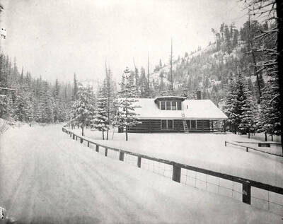 View of a log house covered in snow.
