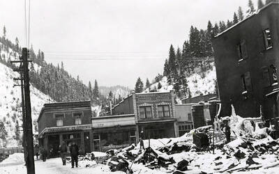 The aftermath of the fire at the Ryan Hotel on Cedar Street in Wallace, Idaho. People can be seen standing outside Theodore's Clothing store across the street.