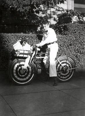 A boy riding a bike with his dog in the basket at the Veterans pet parade in Wallace, Idaho.