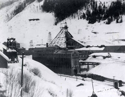 View of the snow slide in Burke, Idaho. Buildings and trees are covered in snow.