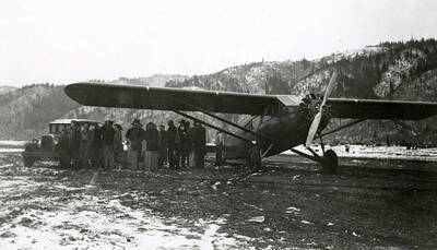 View of airport during the Placer Creek Flood in Wallace, Idaho. A group of people can be seen standing near and airplane.