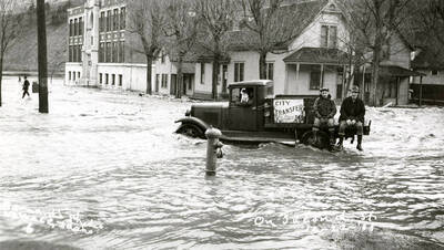 Two men sitting on a truck on Second Street during the Placer Creek flood in Wallace, Idaho.