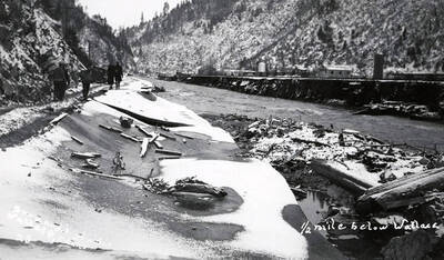 View one half mile below Wallace, Idaho during the Placer Creek flood. People are walking on the road next to the hill.