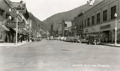 Looking east on Cedar Street in Wallace, Idaho. Cars are parked out in front of stores, which line the street.