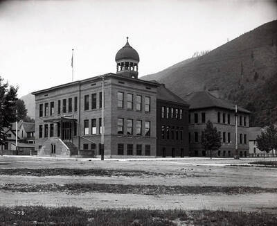 Exterior view of the Wallace High School building. This brick building sports an American flag and a cupola/clock & bell tower on the roof.