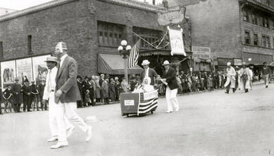 A group of people walking in the Elks parade in Wallace, Idaho, while people stand along the side watching.