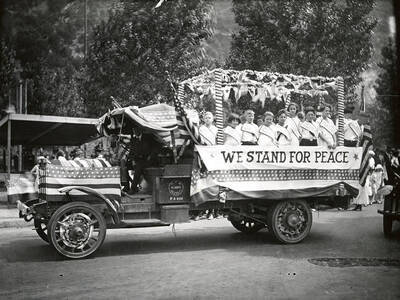 A group of children standing on the Peace float in the Fourth of July Parade in Wallace, Idaho. The children are wearing sashes with different countries' names on them.
