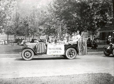 A group of people riding on the "13 Original States" floats during the Fourth of July Parade in Wallace, Idaho.