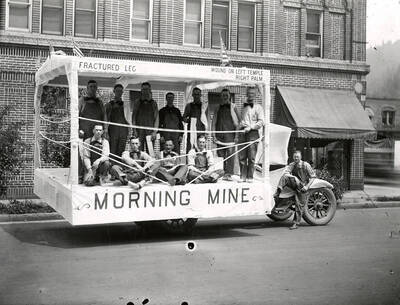 A group of men standing and sitting on the Morning Mine float in the Fourth of July Parade in Wallace, Idaho.