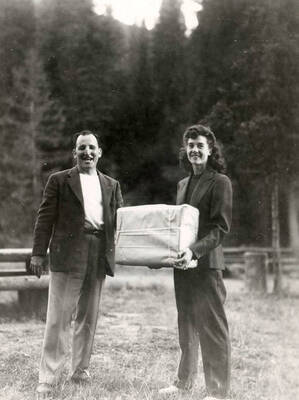 Two people standing together, holding a package during Wallace Jaycee's picnic in Pottsville, Idaho.