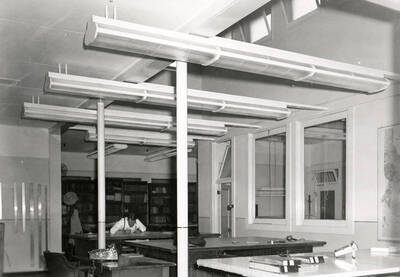 Interior view of the Day Mines Engineering office in Wallace, Idaho. A man can be seen working at one of the desks.