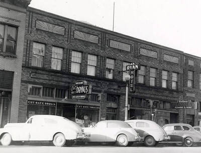 Exterior view of Ryan Hotel in Wallace, Idaho. A drug store can be seen to the left of the hotel and a florist to the right.