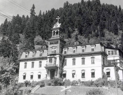 Exterior view of Providence Hospital in Wallace, Idaho. A hill covered in trees can be seen behind the hospital.