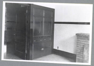 A brick fireplace and hideable kitchenette with its doors closed in an upstairs apartment in the Barnard Building in Wallace, Idaho.