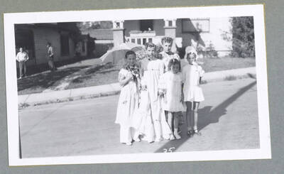 Two children in costume posing beside a wagon during the Children's Parade.