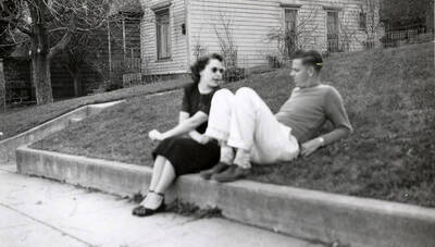 Two people sitting on the grass during the Our Lady of Lourdes Academy Blessed Virgin procession in Wallace, Idaho.