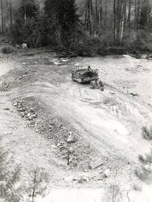 Construction machinery on a Colonial Construction Company worksite near a small creek.