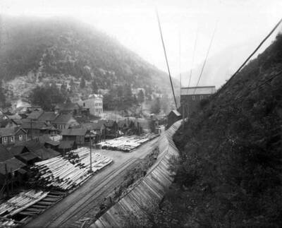 Exterior view of Marsh Mine showing several buildings, stacks of logs and a covered tunnel made of wood. Taken Sept. 29, 1910.