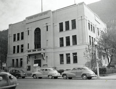Exterior view of the Shoshone County Courthouse in Wallace, Idaho. Cars can be seen parked in front of the courthouse.