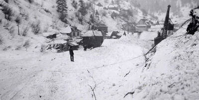 A person watching a crane remove snow after the snow slide in Mace, Idaho.