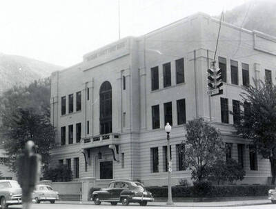 Exterior view of the Shoshone County Courthouse in Wallace, Idaho. Cars can be seen parked in front of the courthouse.
