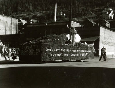A float reading "Liberty enlightening the world. Don't let the red tide of communism put out the torch of liberty" on the side during the Elks Parade in Wallace, Idaho.