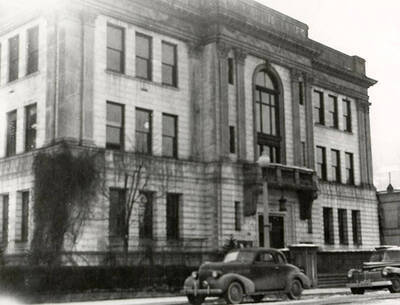 Exterior view of the Shoshone County Courthouse in Wallace, Idaho. A few cars can be seen parked in front of the building.