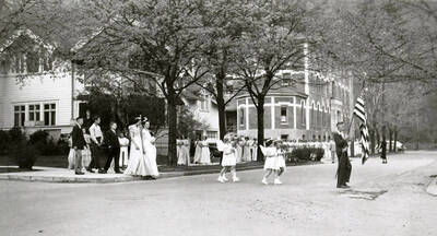 Children in pairs following a boy holding an American flag across the road to Our Lady of Lourdes Academy during the Blessed Virgin Procession in Wallace, Idaho.