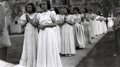 Children lined up in pairs on the sidewalk outside of Our Lady of Lourdes Academy during the Blessed Virgin Procession in Wallace, Idaho.