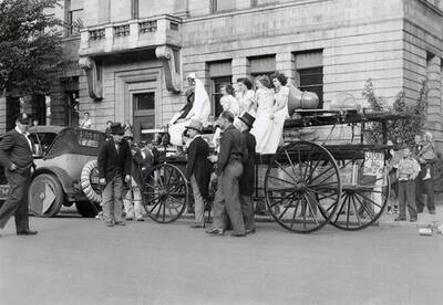 Girls sitting on a float, with men standing next to it during the Elks Roundup parade in Wallace, Idaho.