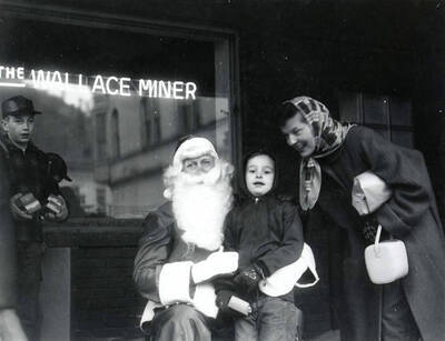 Santa Claus sitting with children in front of the Wallace Miner window.