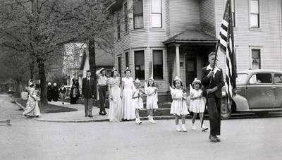 Children in pairs following a boy holding an American flag across the road to Our Lady of Lourdes Academy during the Blessed Virgin Procession in Wallace, Idaho.