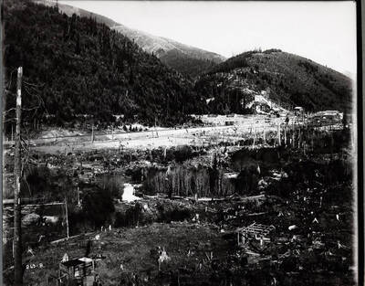 Distant view of stumps and wooden out-buildings with mine buildings in the far distance. Caption on front: "Snowstorm Mine, Mullan, Idaho by Craig - lawsuit over ranch."
