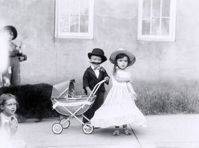 Two small children posing in costume next to a baby carriage during the 49'er Parade in Mullan, Idaho.