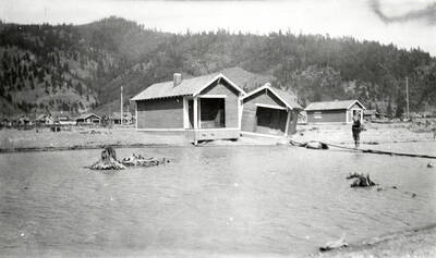 The Sunnyside Addition in Kellogg, Idaho during the flood of 1933. A man can be seen standing on a makeshift bridge outside a house.