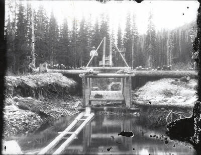 Ruphe Dunlap and Archie Smith standing on a weir (a low dam built across a river to raise the level of water upstream or regulate its flow) at East Eagle Creek in Murray, Idaho.